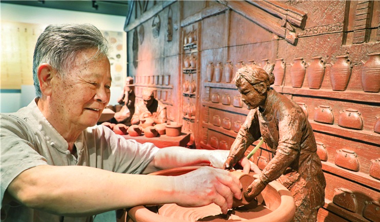 中国工艺美术大师徐秀棠与他创作的《前墅窑场生产流程群雕》。
