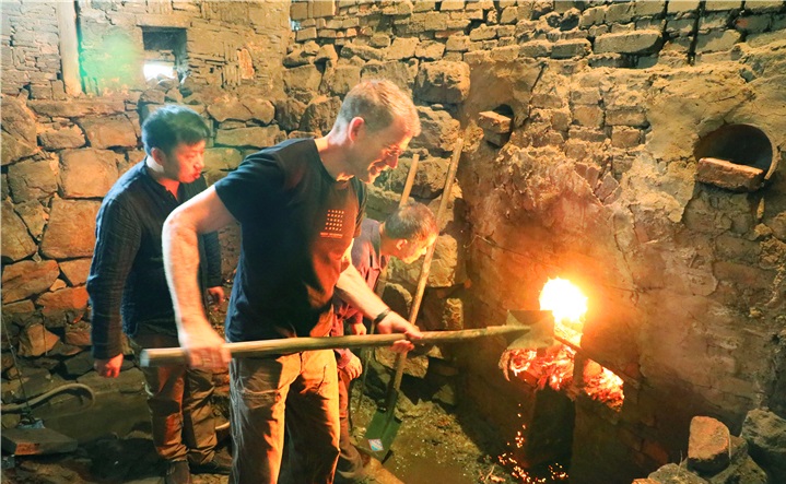 2019年10月14日，美国一位陶艺家在体验为龙窑添火。  